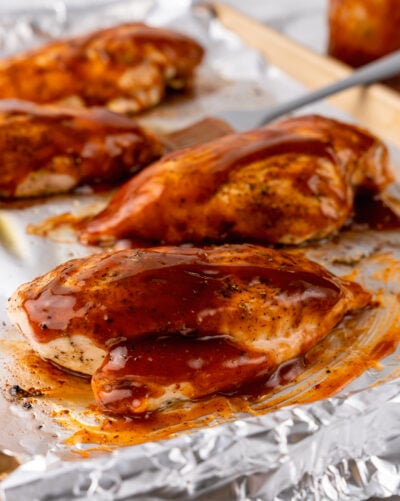 Oven-baked BBQ chicken breasts glazed with sauce on a foil-lined pan.