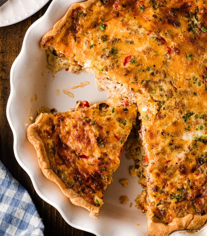 Pimento cheese sausage quiche with a slice served from a golden baked pie crust.
