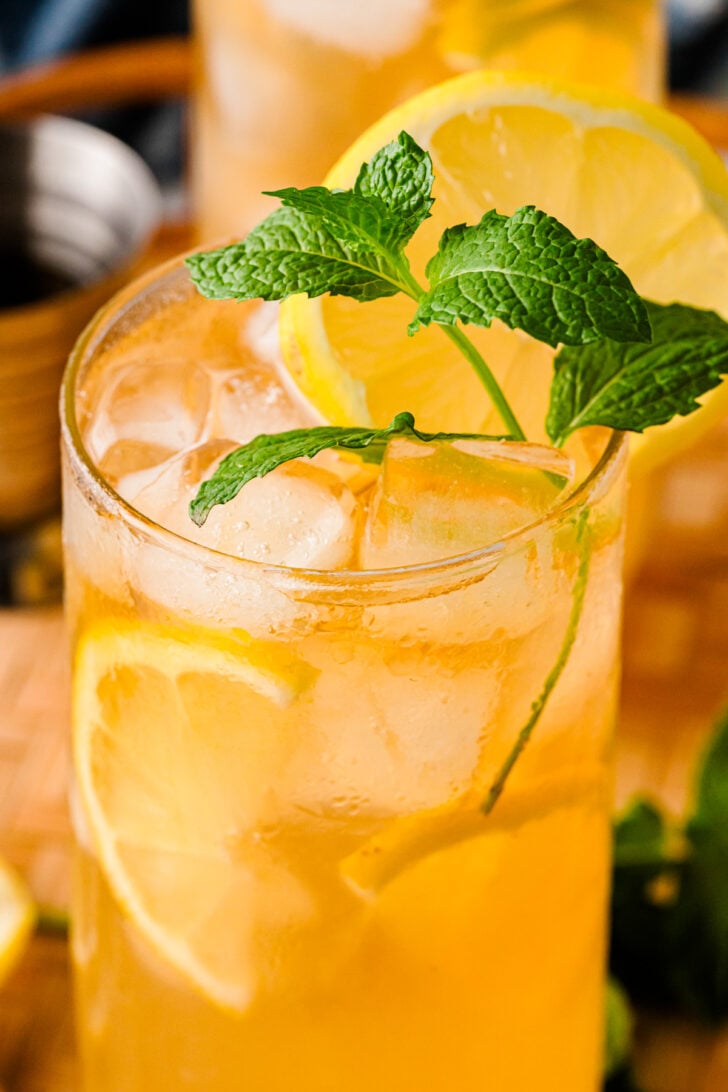 Bourbon Arnold Palmer cocktail garnished with mint and lemon.