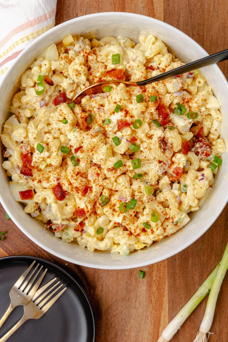 Deviled egg pasta salad in a bowl with green onions and paprika.