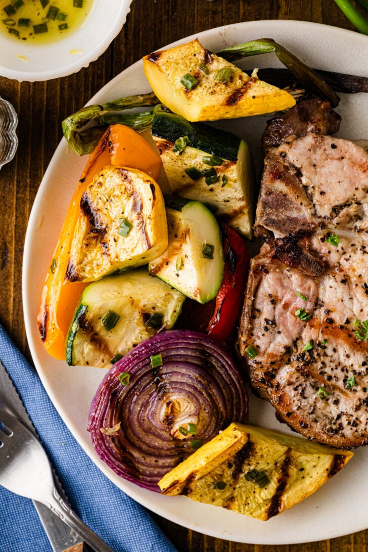 Grilled vegetables and pork chop on a plate.