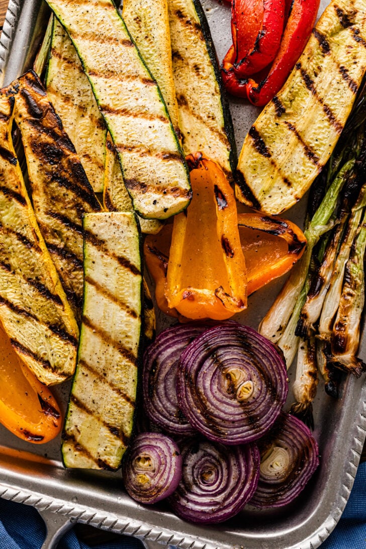 Grilled zucchini, peppers, and onions on a baking tray.