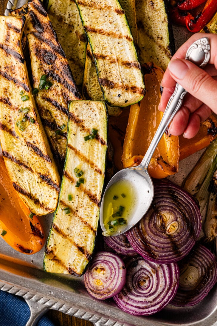 Drizzling dressing over grilled zucchini, peppers, and onions.