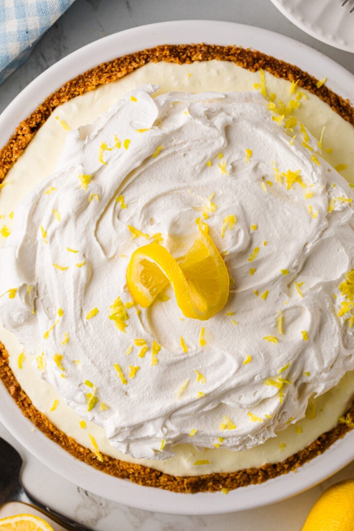 Whole lemon icebox pie topped with whipped cream and a lemon twist.