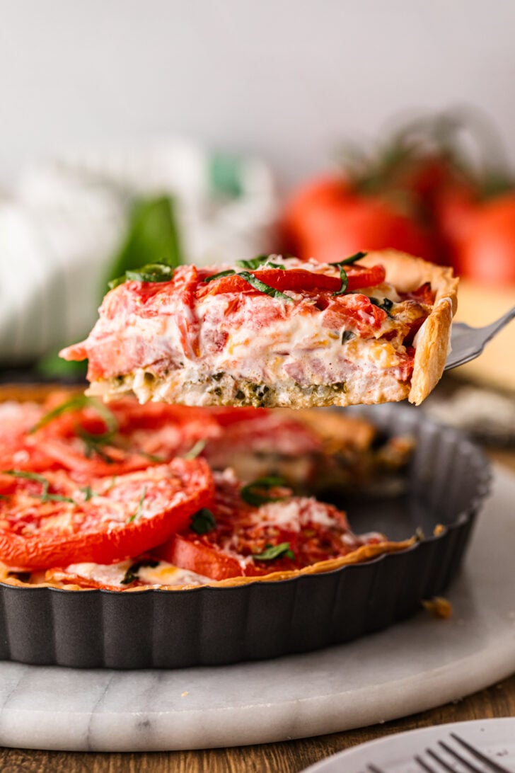 Slice of tomato pie lifted from the pan on a fork.