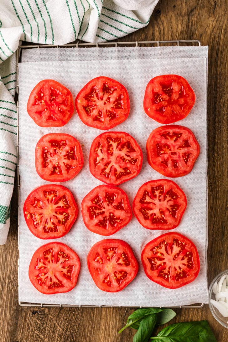 Sliced tomatoes draining on paper towels for tomato pie.