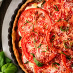 Overhead view of tomato pie topped with cheese and basil.
