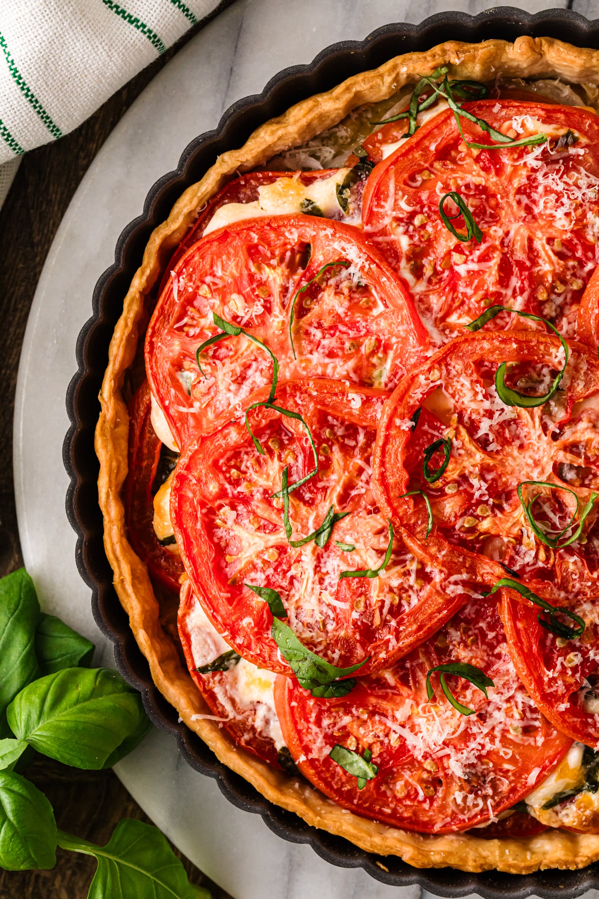 Overhead view of tomato pie topped with cheese and basil.