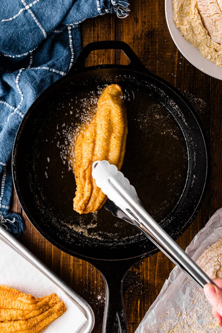 Catfish fillet frying in hot oil in a cast iron skillet