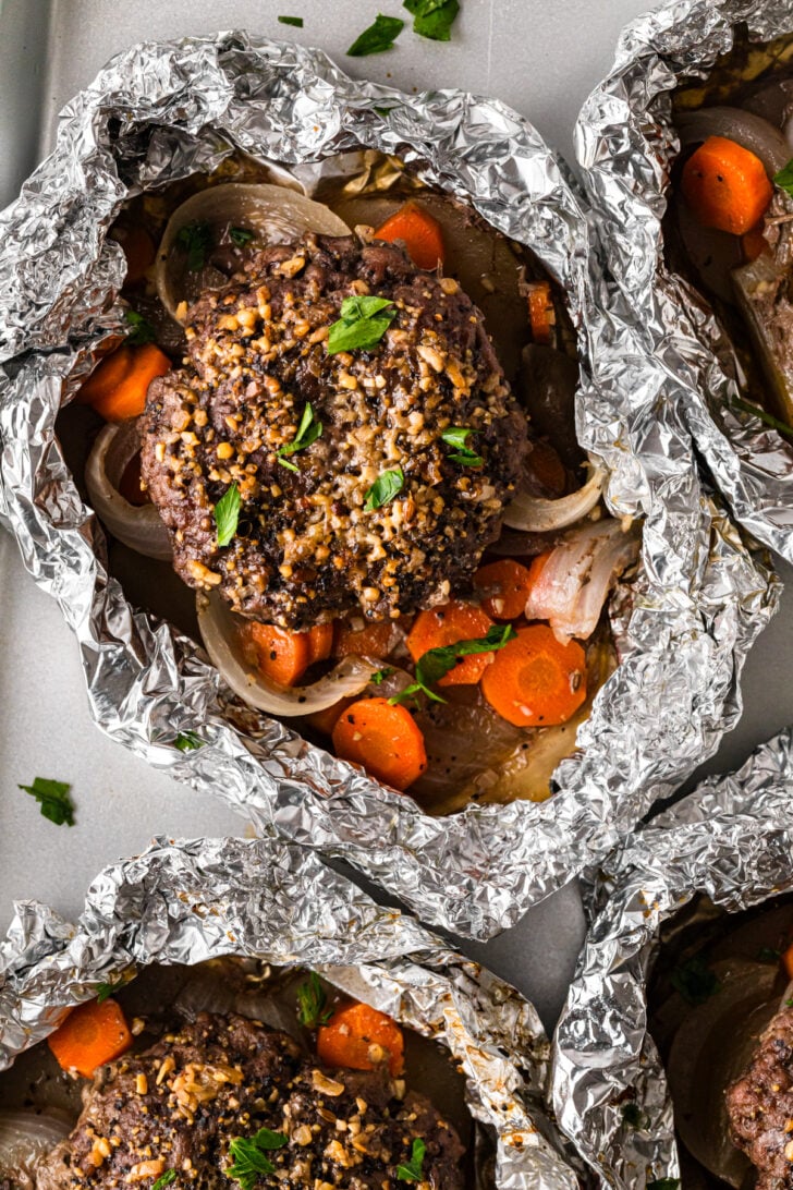 Hobo foil packs with burger patties, carrots, and onions.