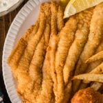 Close-up of fried catfish fillets on a plate with lemon wedges