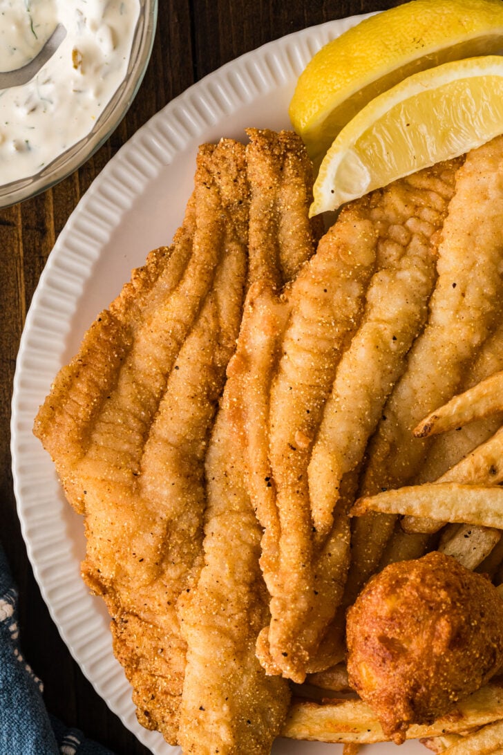 Close-up of fried catfish fillets on a plate with lemon wedges