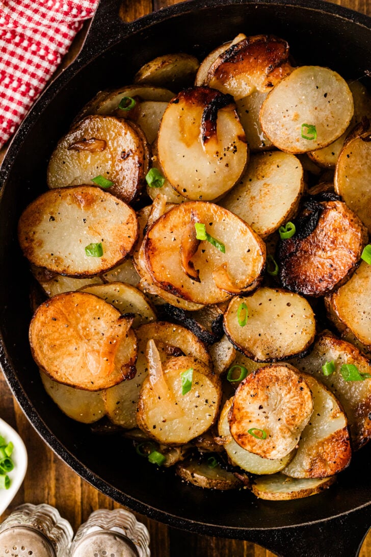 Close-up of golden fried potatoes and onions cooked in a cast iron skillet
